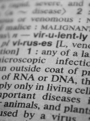 Black and white close-up of a dictionary page focusing on the definition of 'virus'.