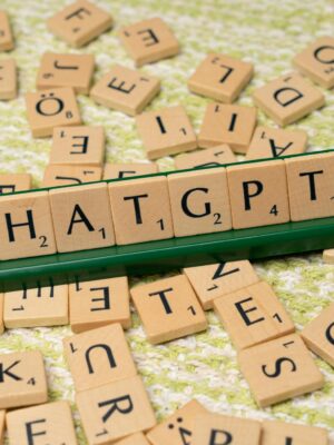 Scrabble game spelling 'CHATGPT' with wooden tiles on textured background.